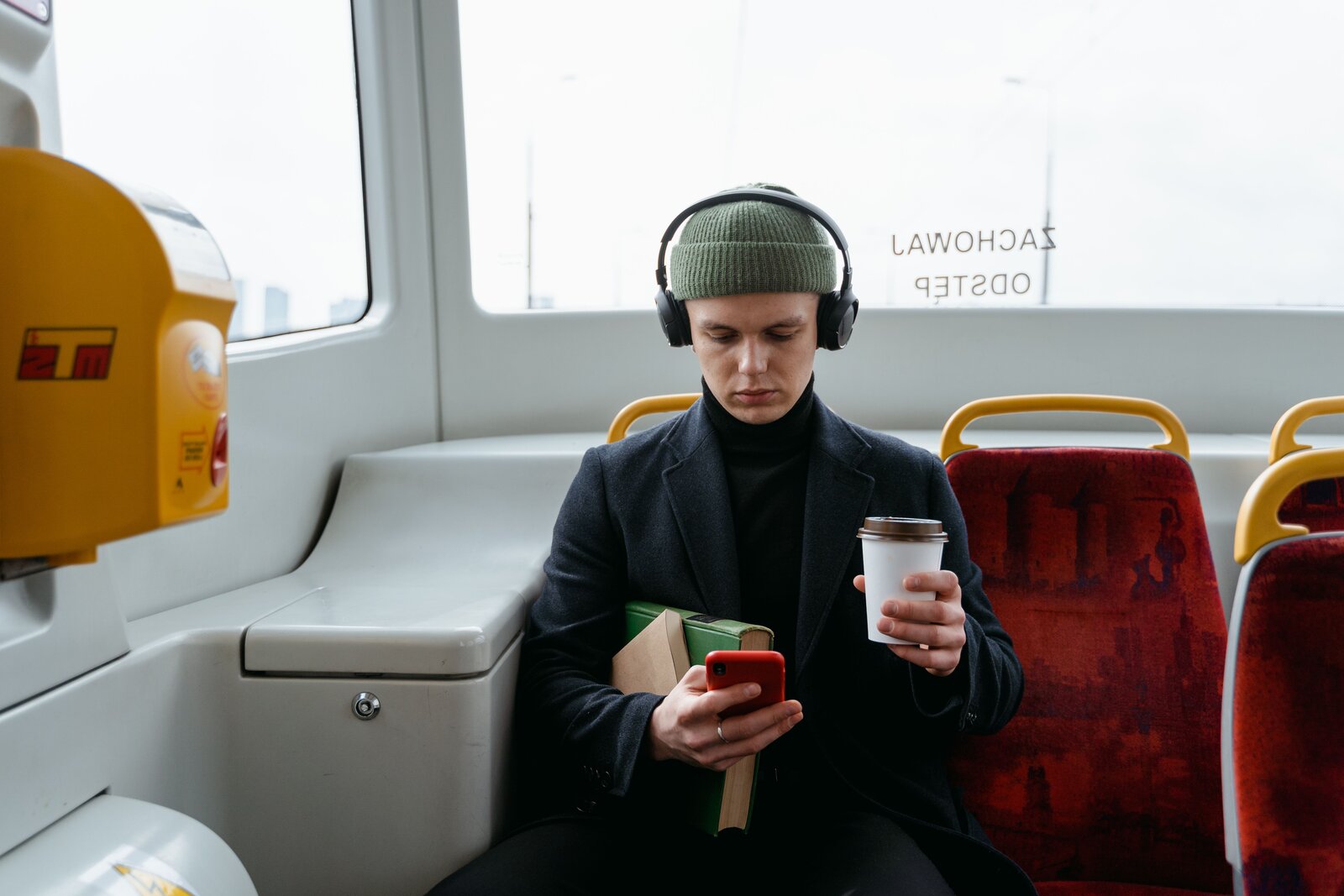 Un passager dans un bus, téléphone et café à la main